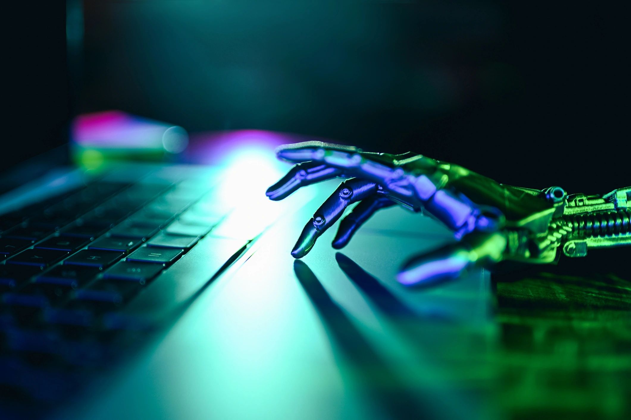 Robot hand touching a laptop keyboard representing artificial intelligence