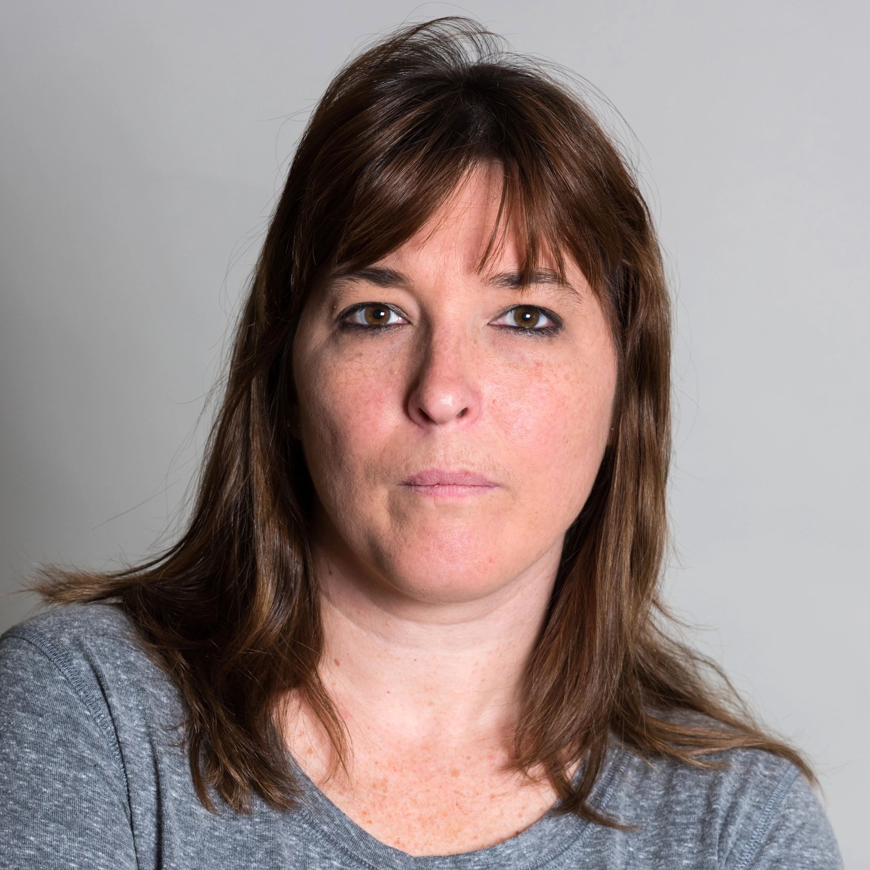 Portrait headshot of a mature woman on a gray background